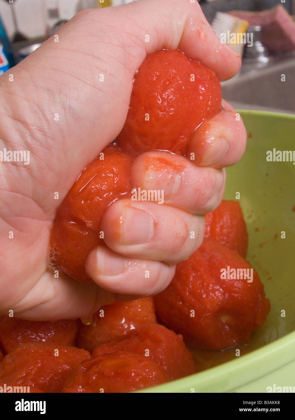 Un cuisinier serrant dans son poing les tomates pelées Banque D'Images