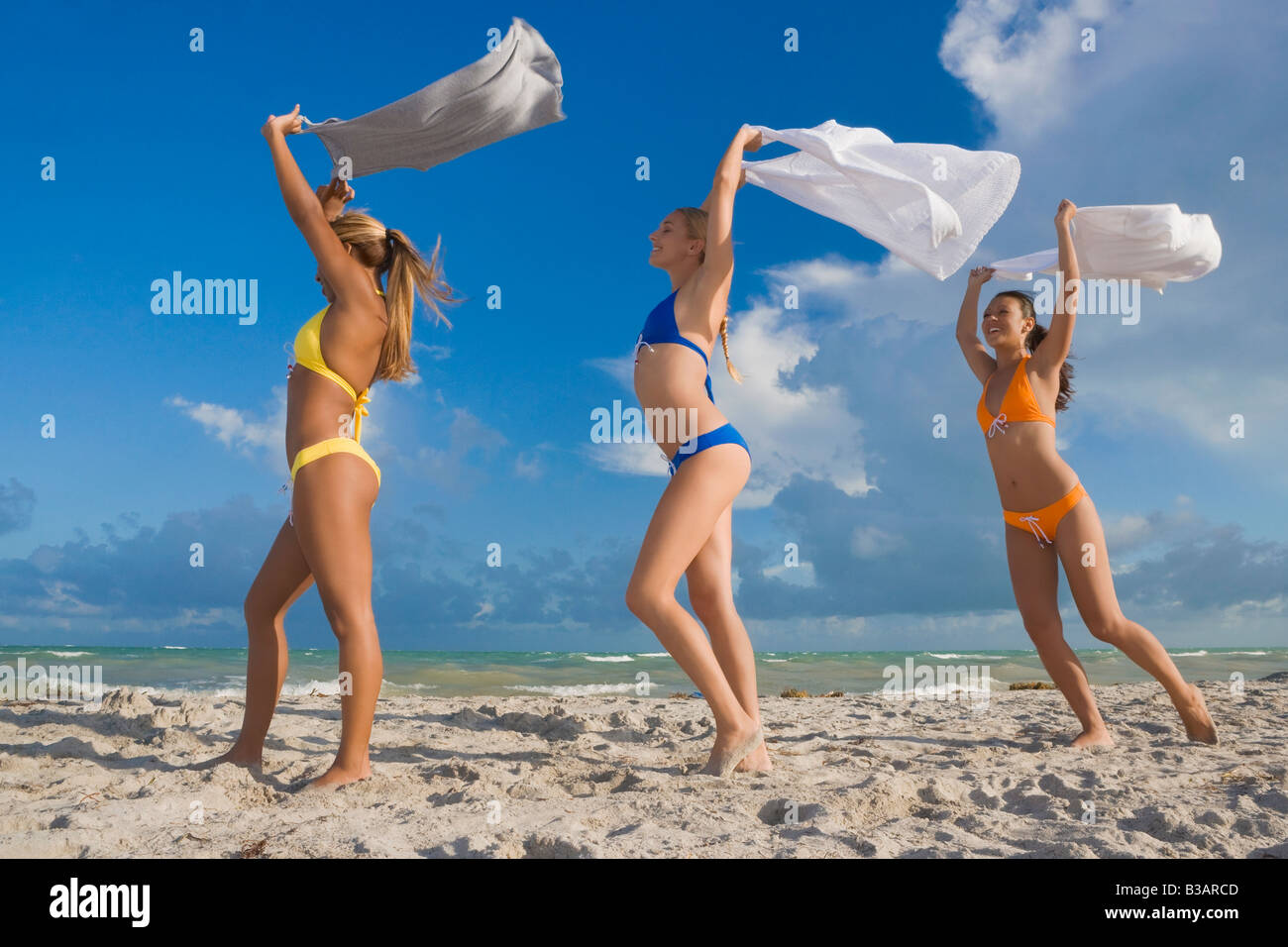 Les femmes hispaniques dans des bikinis holding jupes dans le vent Banque D'Images