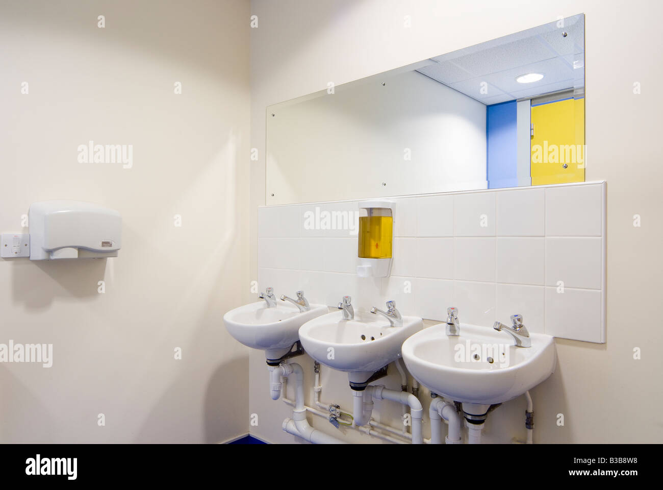 Rangée de lavabos et sèche-mains électrique dans une zone de Bain toilettes dans une école ou un bureau place au Royaume-Uni Banque D'Images