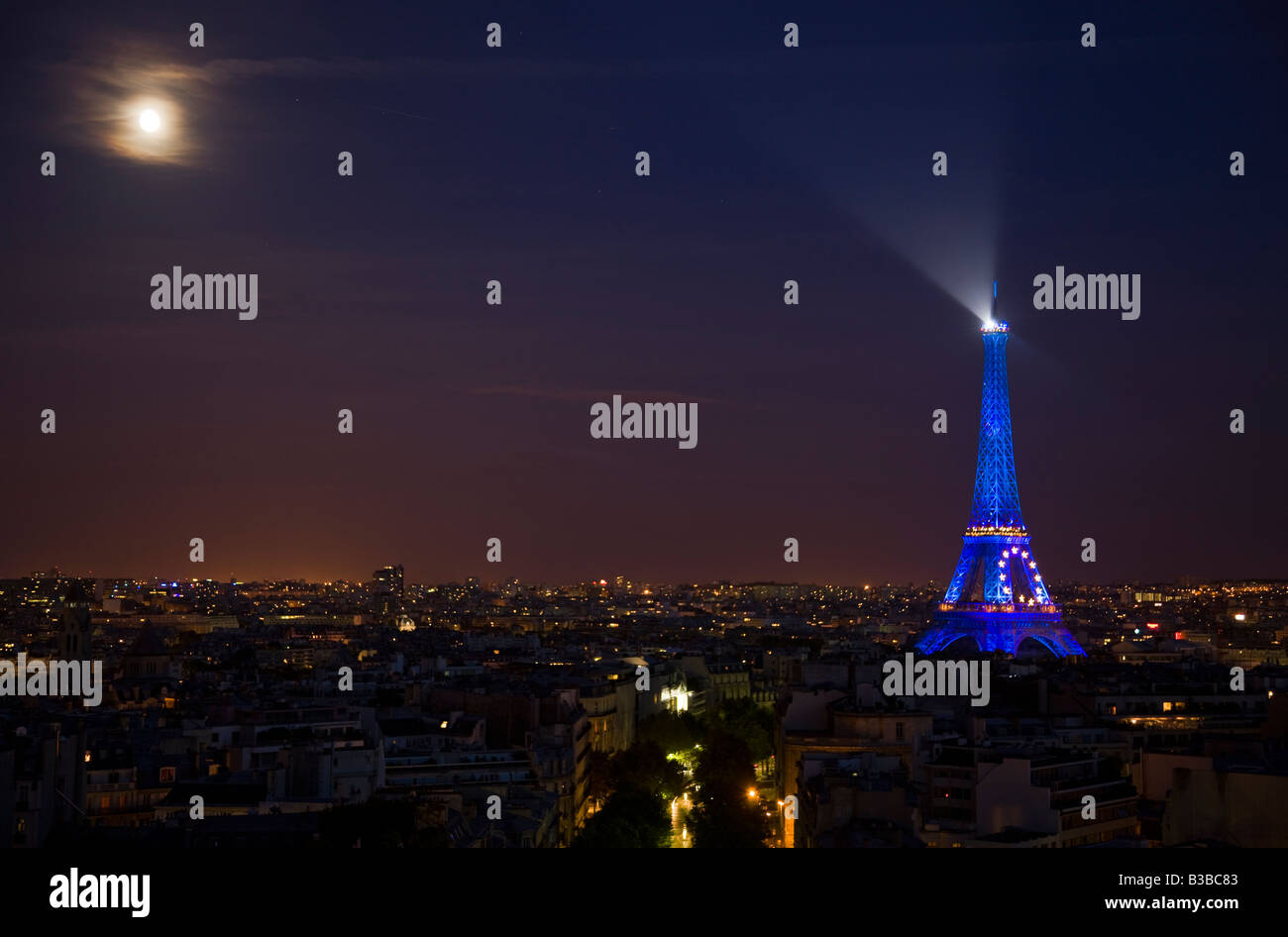Célèbre attraction Tour Eiffel avec feux bleus au crépuscule rougeoyant pleine lune à travers les nuages vaporeux destination touristique Paris paysage urbain de nuit Banque D'Images