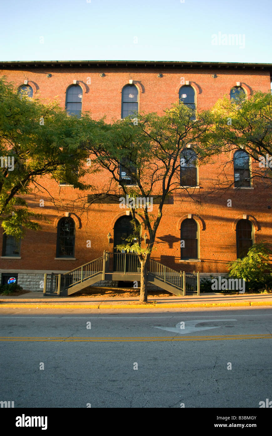 Un bâtiment en briques rouges avec l'arbre de Ginkgo à l'avant est mis en évidence par le soleil l'après-midi au plus tard Banque D'Images