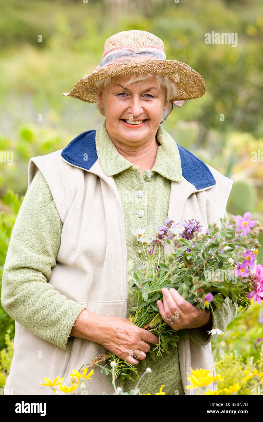 Portrait de femme en prairie, fleurs de collecte Banque D'Images