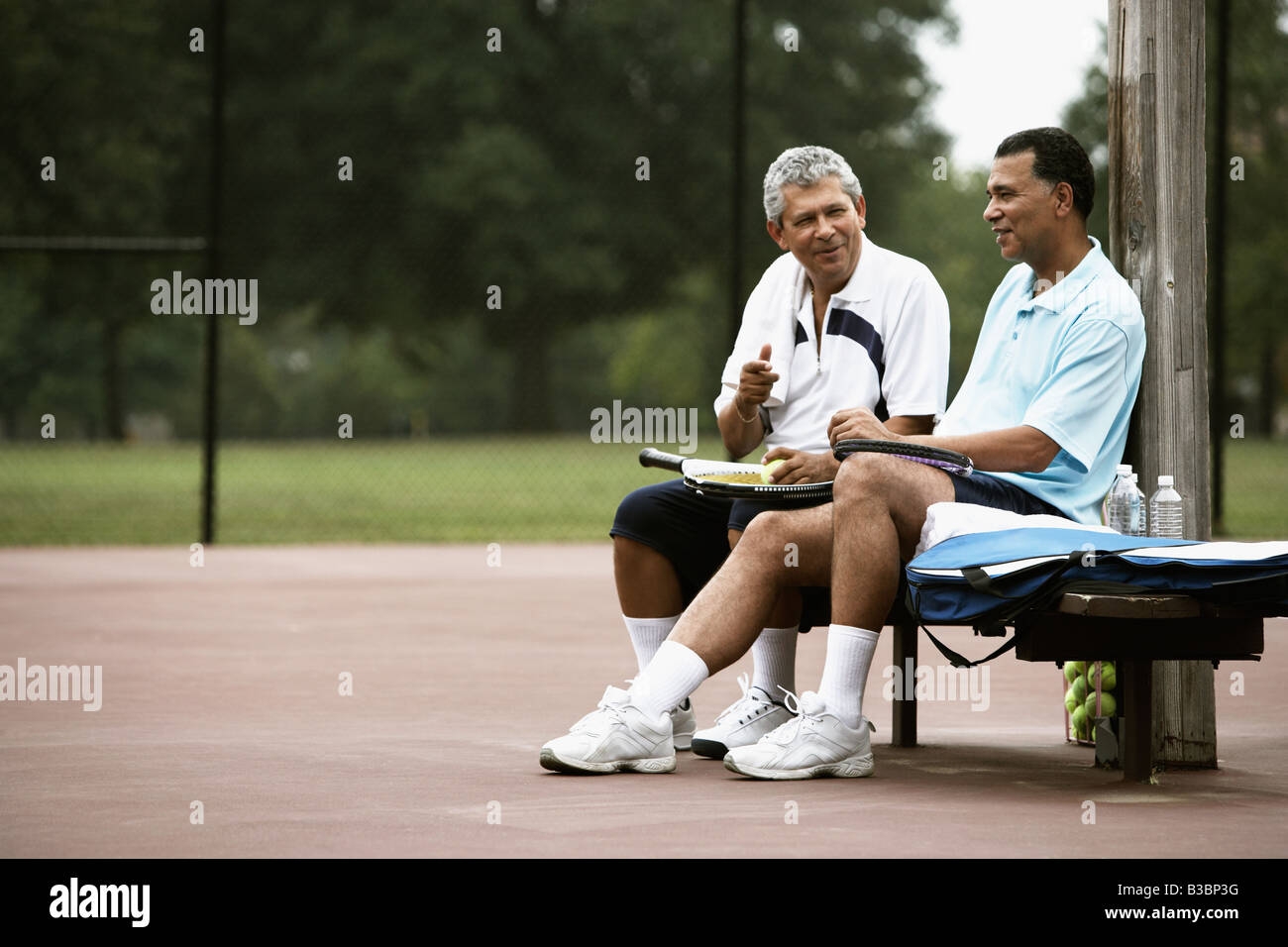 Multi-ethnic hommes parler sur court de tennis Banque D'Images