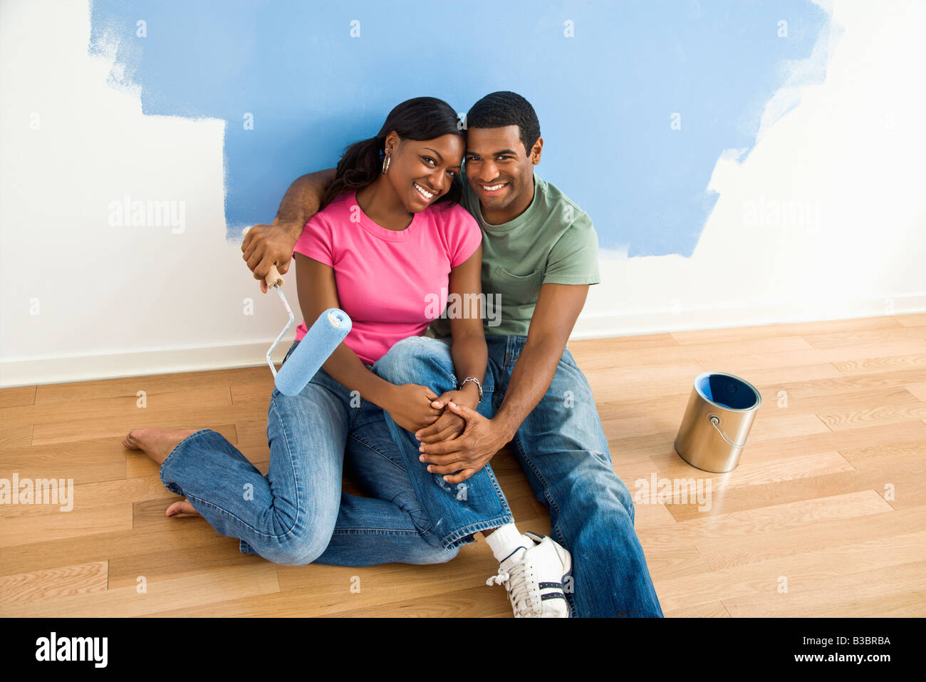 African American couple de détente à côté de la moitié du mur peint et fournitures peinture Banque D'Images