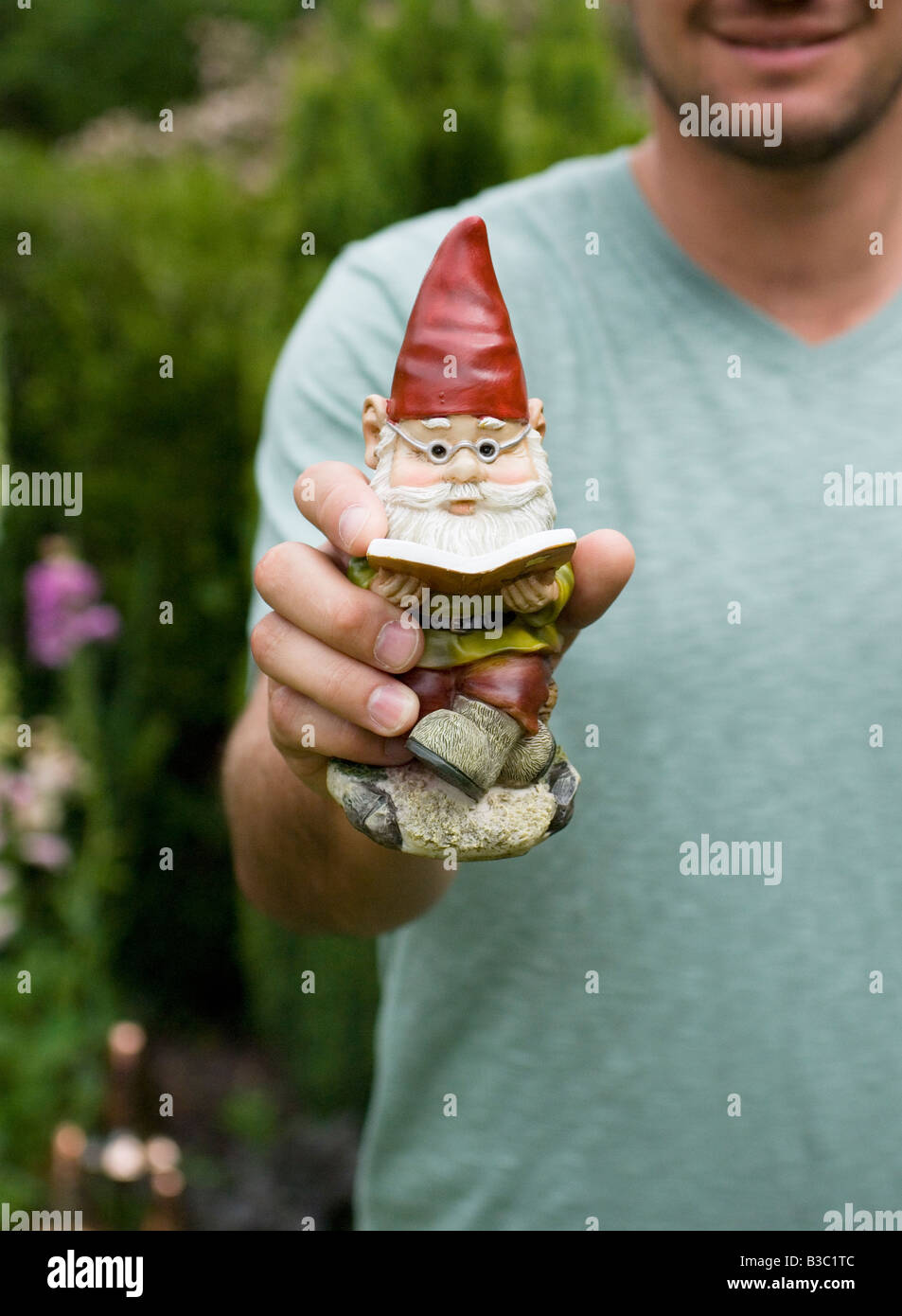 Un homme tenant un nain de jardin Banque D'Images