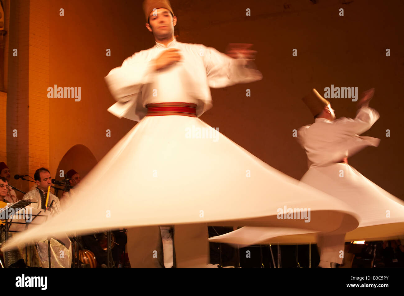 Maroc, Fes. Deux Derviches tourneurs effectuer lors d'un concert au Festival de Fès des Musiques Sacrées du Monde. Les membres de l'Ensemble Al Kindi effectuer la musique. Banque D'Images