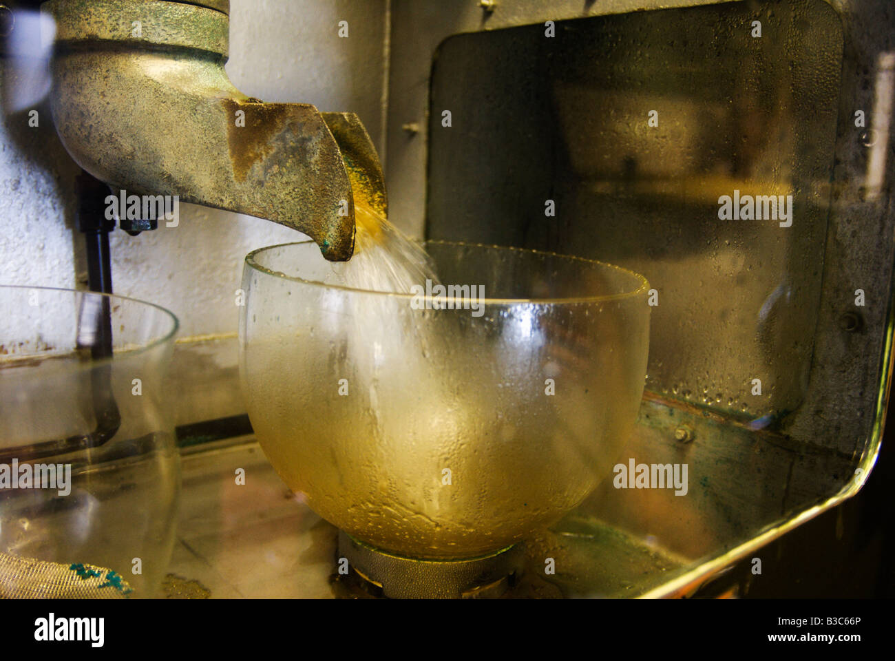 La pression d'eau qui se déverse du whisky alcool esprit distiller du whisky distillerie production production de verre de sécurité verre bol bourbon Banque D'Images