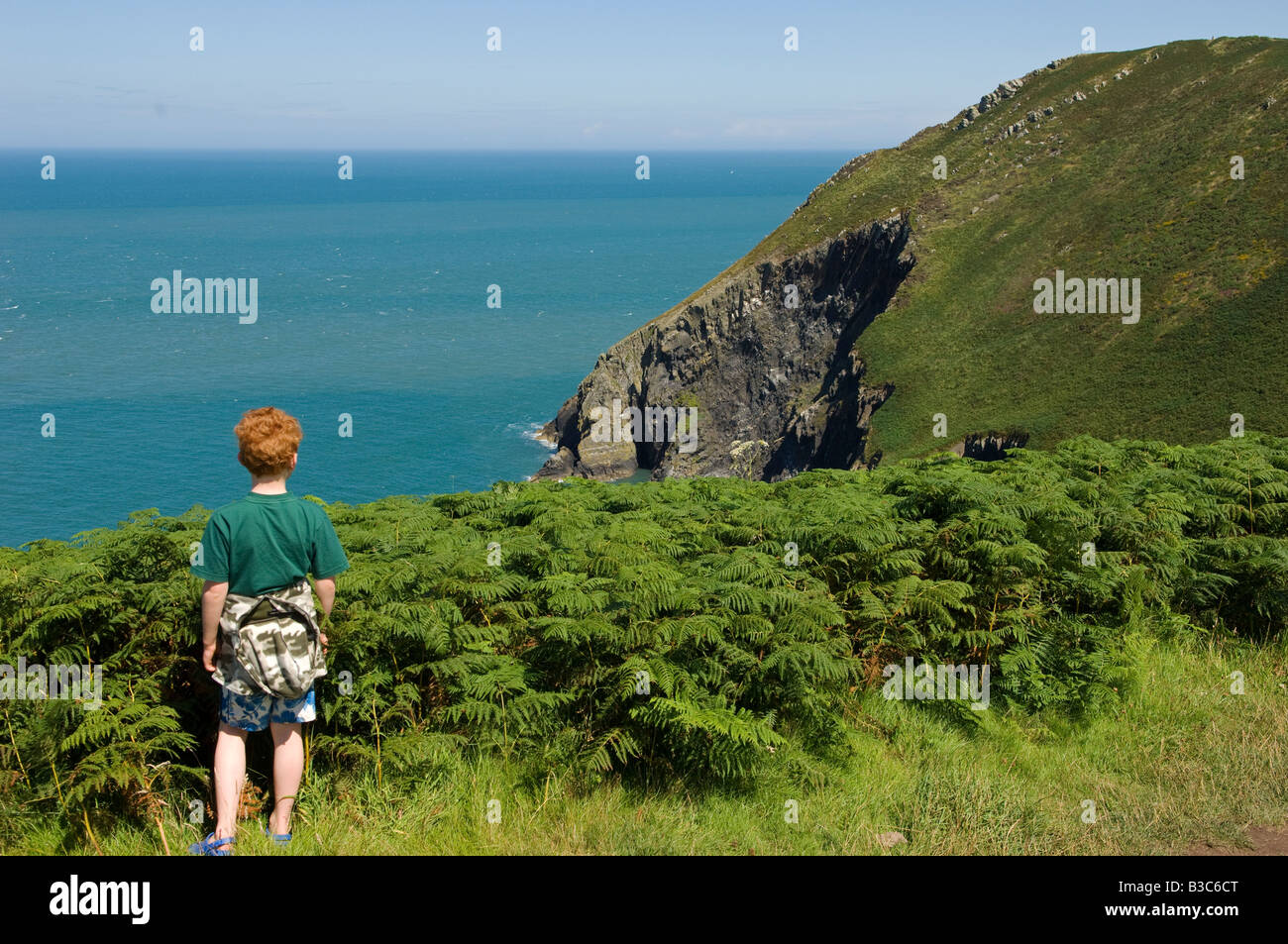 Royaume-uni, Pays de Galles, Pembrokeshire. Un jeune garçon regarde à partir de la Dinas tête sur une promenade le long du sentier côtier du Pembrokeshire (MR). Banque D'Images