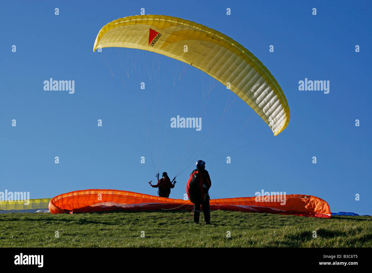 L'Angleterre, Eastbourne, East Sussex. Le parapente est un sport de vol récréatifs et compétitifs. Un parapentiste est un battant, lancé des avions. Le pilote est assis dans un harnais suspendu au-dessous un tissu d'une aile, dont la forme est constituée par la pression d'air entrant dans les évents à l'avant de l'aile. Banque D'Images