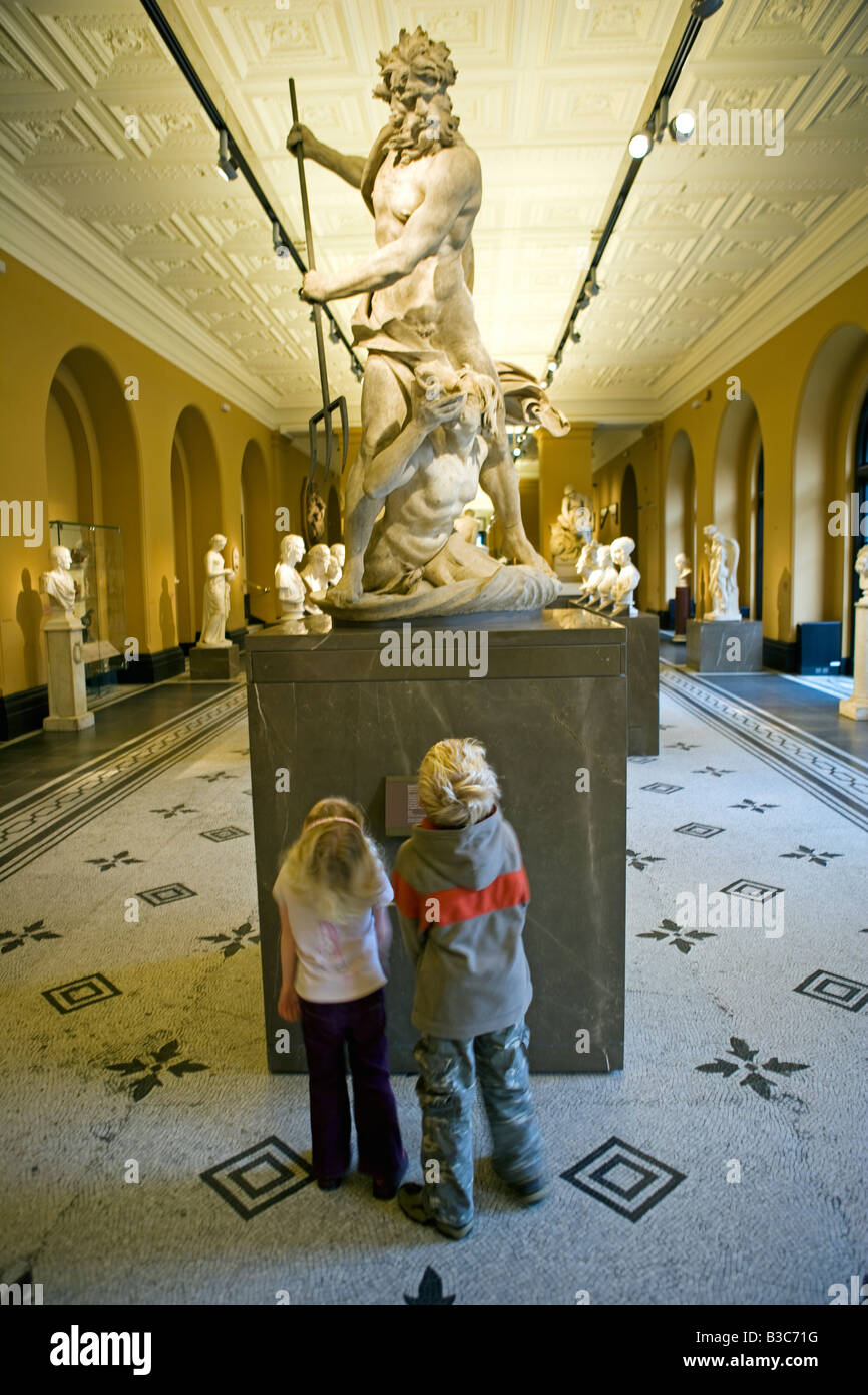 L'Angleterre, Londres, Victoria and Albert Museum. Un frère et une soeur regarder une statue sculptée de façon classique dans l'affichage d'une tribune de l'un des plus importants centres d'accueil des visiteurs. (MR). Banque D'Images