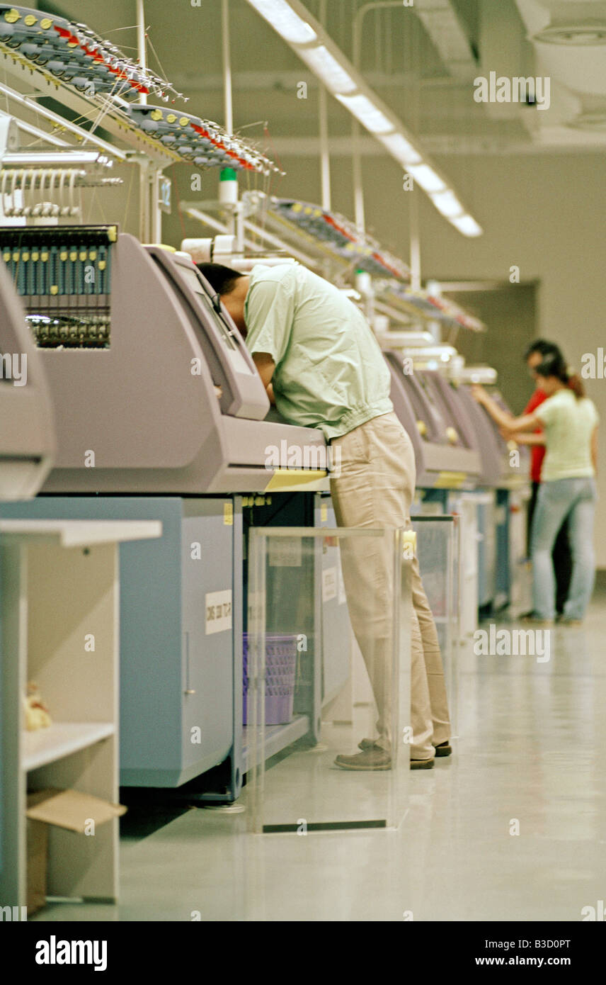 Un travailleur regarde vers le bas dans une machine à tricoter dans une  usine de tricot à Shanghai, Chine Photo Stock - Alamy