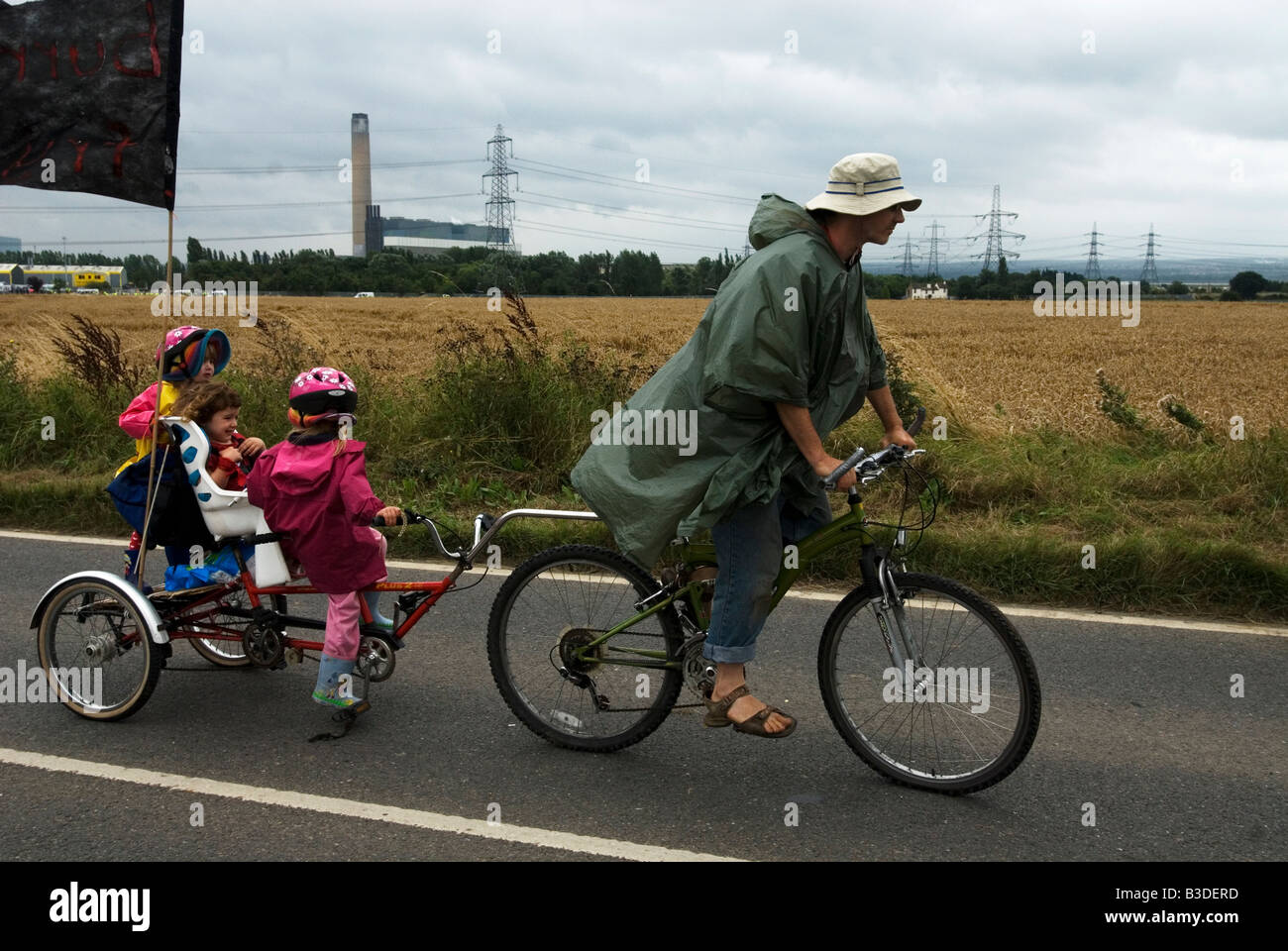 Père à vélo avec les enfants en location chariot pour protester contre la centrale électrique alimentée au charbon Banque D'Images