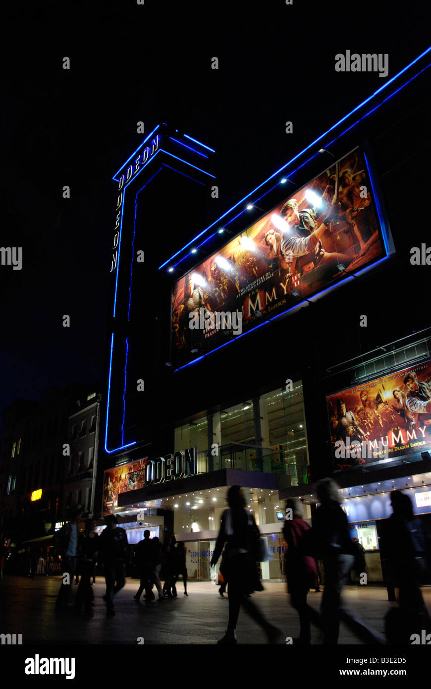 Les femmes passant le cinéma Odeon Leicester Square à Londres la nuit Banque D'Images