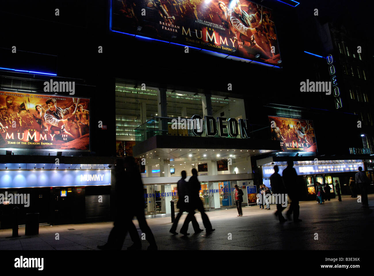 Les gens qui passent l'Odeon Leicester Square Cinema la nuit London England Banque D'Images