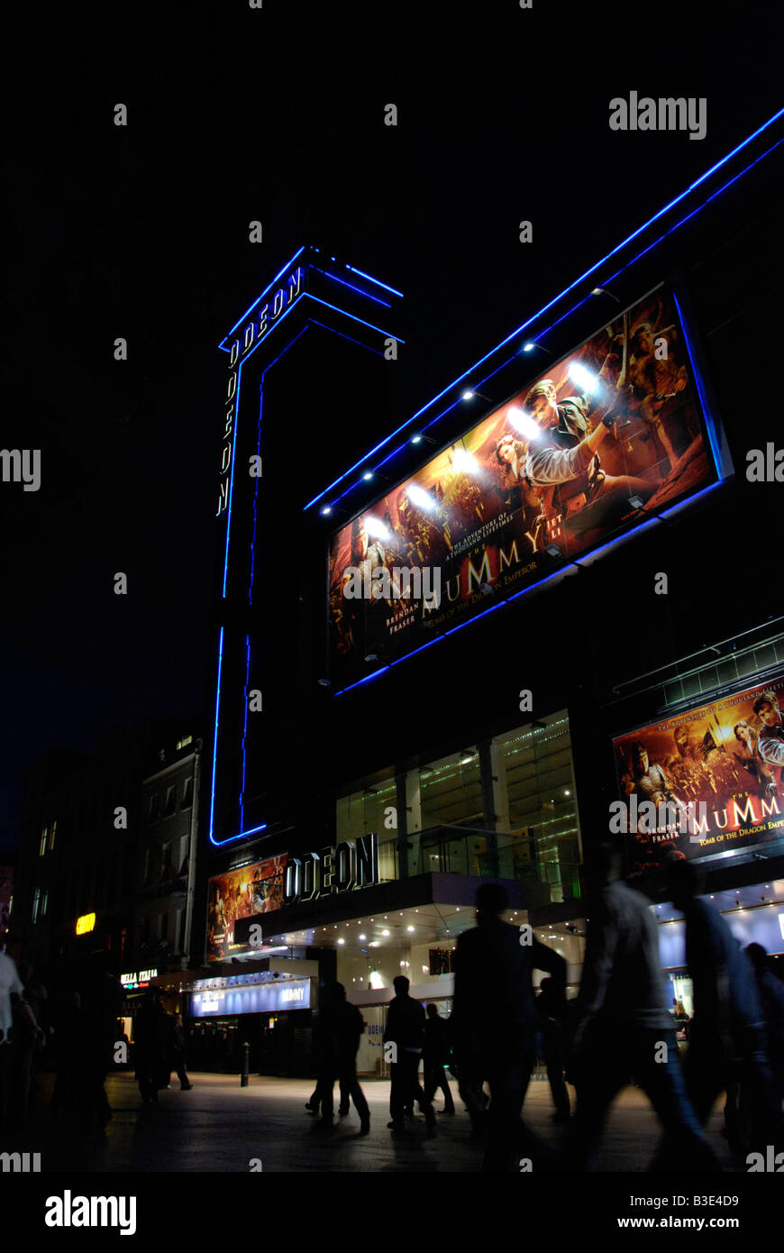 Les hommes passant le cinéma Odeon Leicester Square à Londres la nuit Banque D'Images