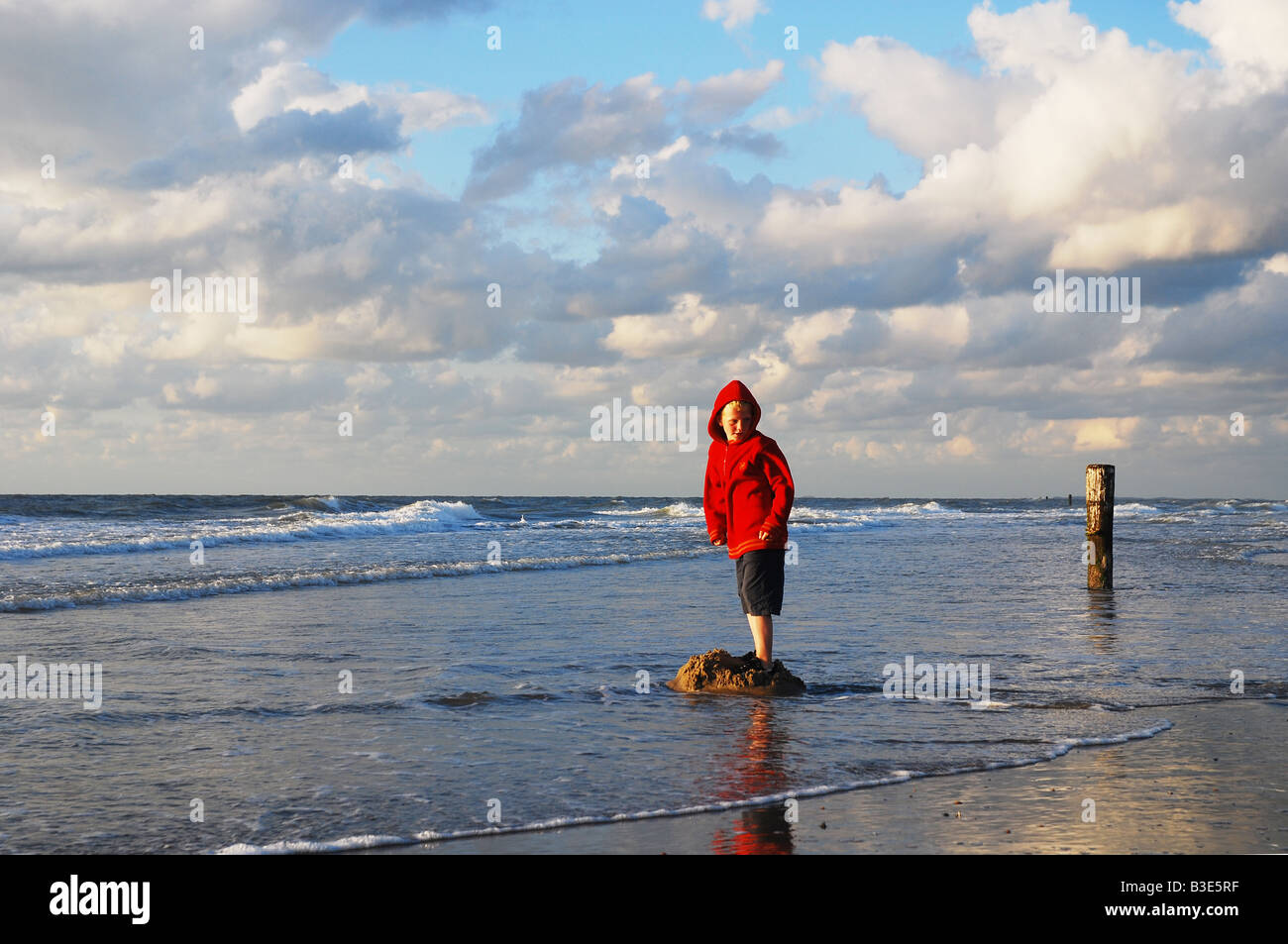 Scène de plage avec petit garçon en rouge Banque D'Images