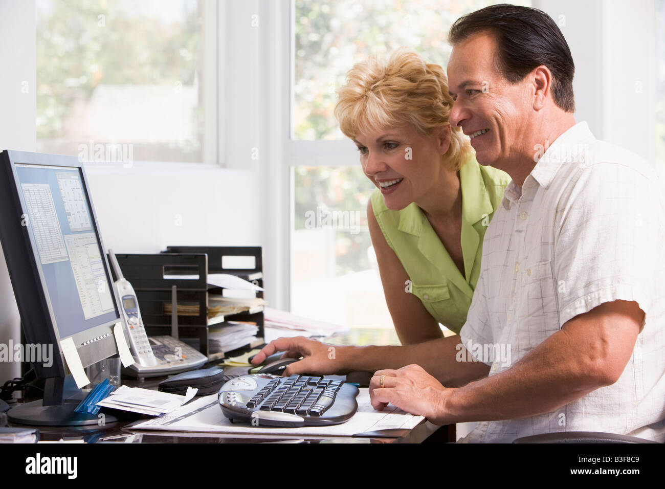 Couple in home office at computer smiling Banque D'Images