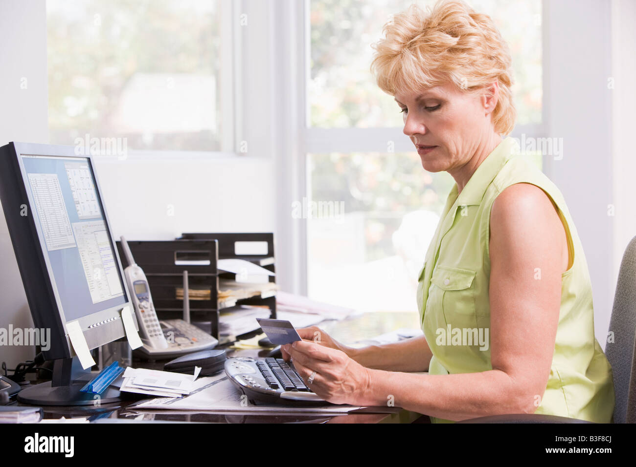 Woman in home office à l'ordinateur avec carte de crédit froncer Banque D'Images Woman in home office à l'ordinateur avec carte de crédit froncer Banque D'Images