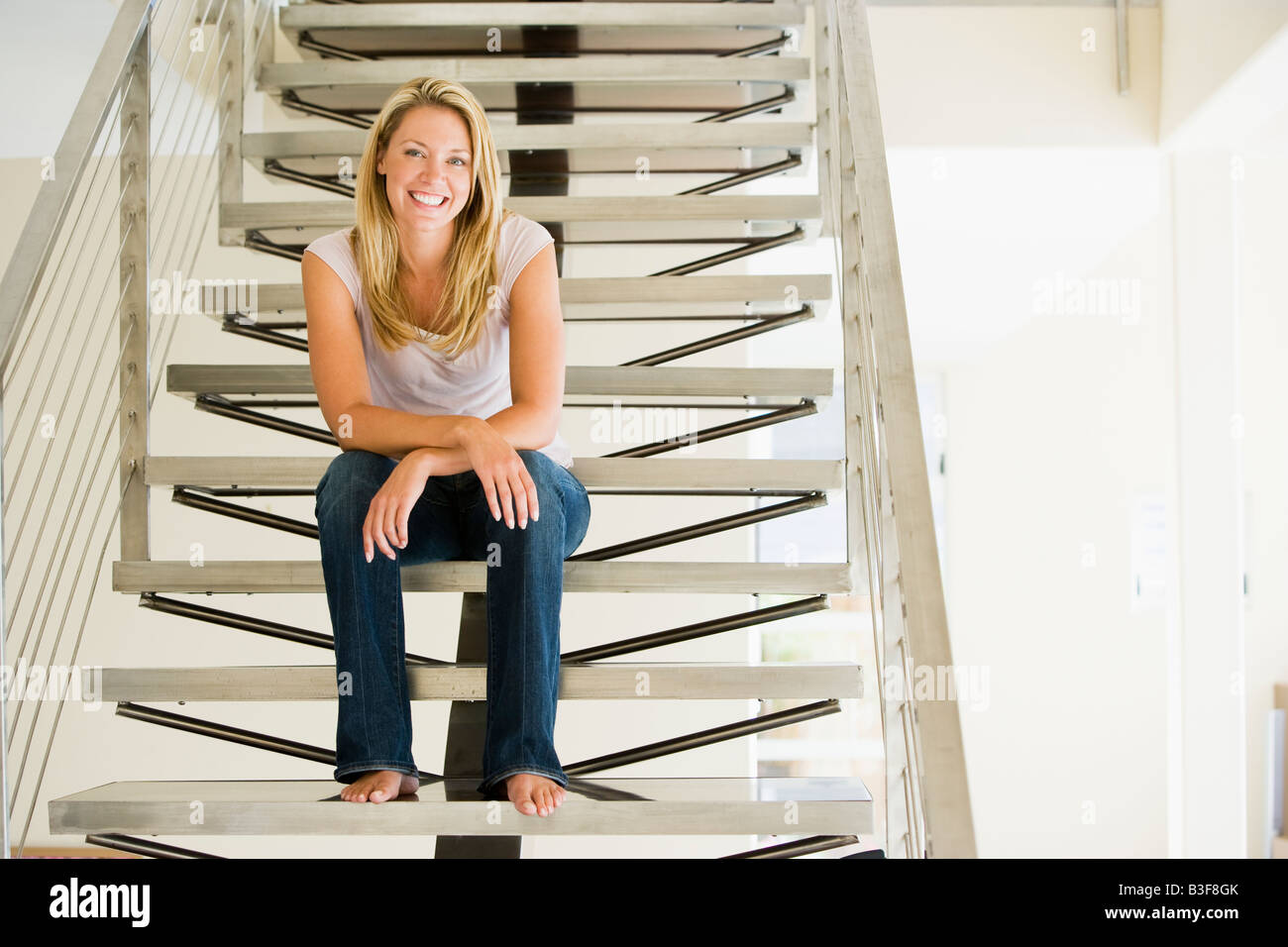 Woman sitting on stairs smiling Banque D'Images