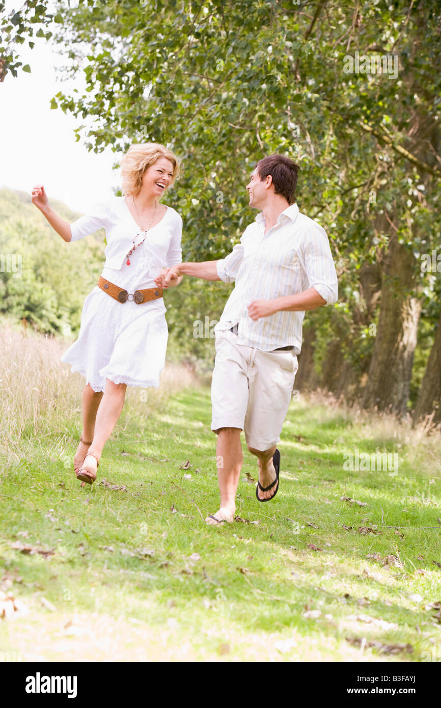 Couple running on path holding hands and smiling Banque D'Images