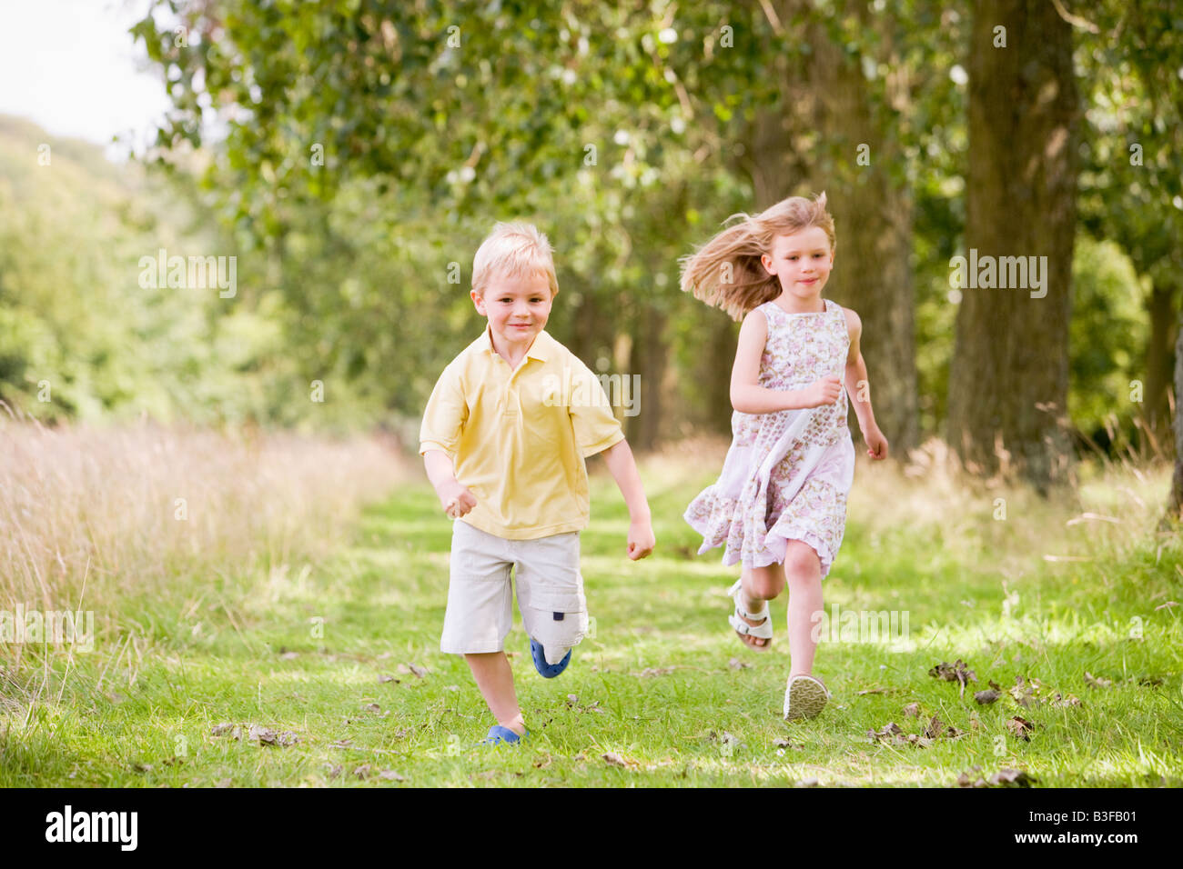 Deux jeunes enfants courir sur chemin smiling Banque D'Images