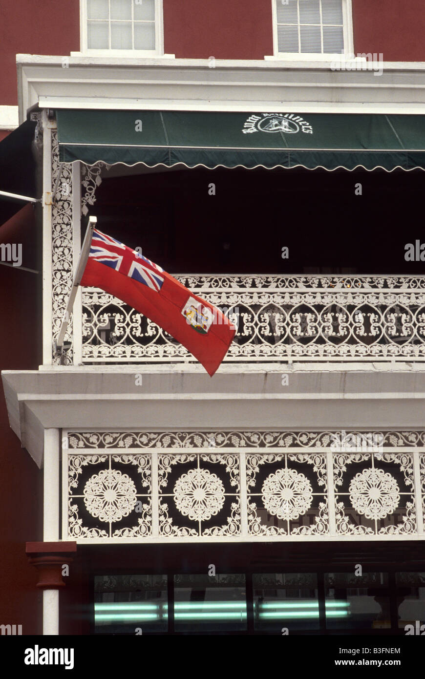 Drapeau bermudien, volant depuis un balcon complexe en fer forgé blanc sur Front Street, Hamilton, Bermudes Banque D'Images