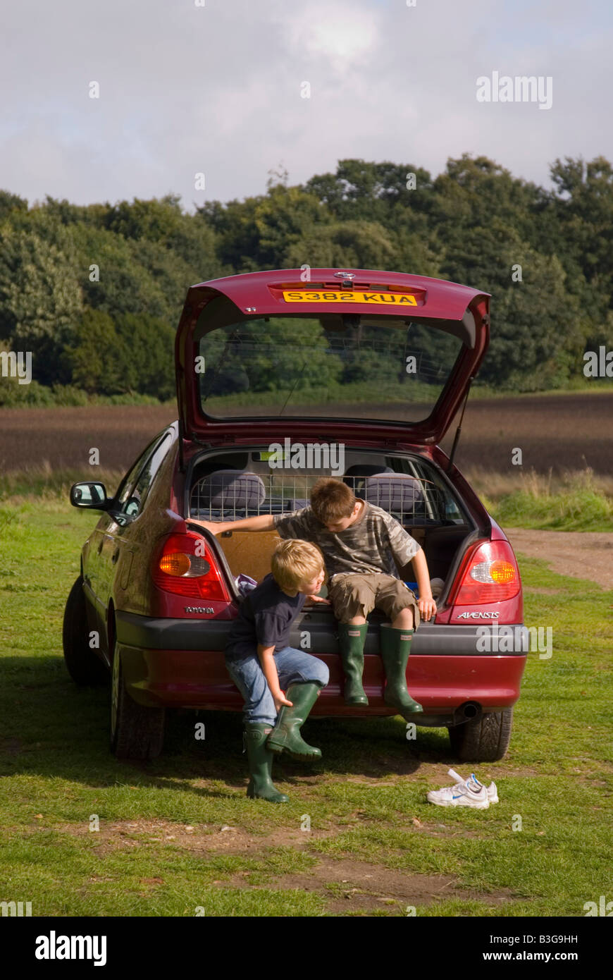 Deux garçons mise sur leurs bottes sur la voiture avant de partir en promenade dans la campagne. Banque D'Images
