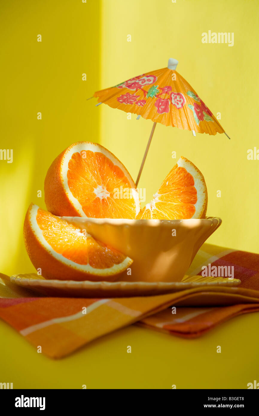 Les oranges en tranches dans un bol et une serviette orange sur fond jaune Banque D'Images