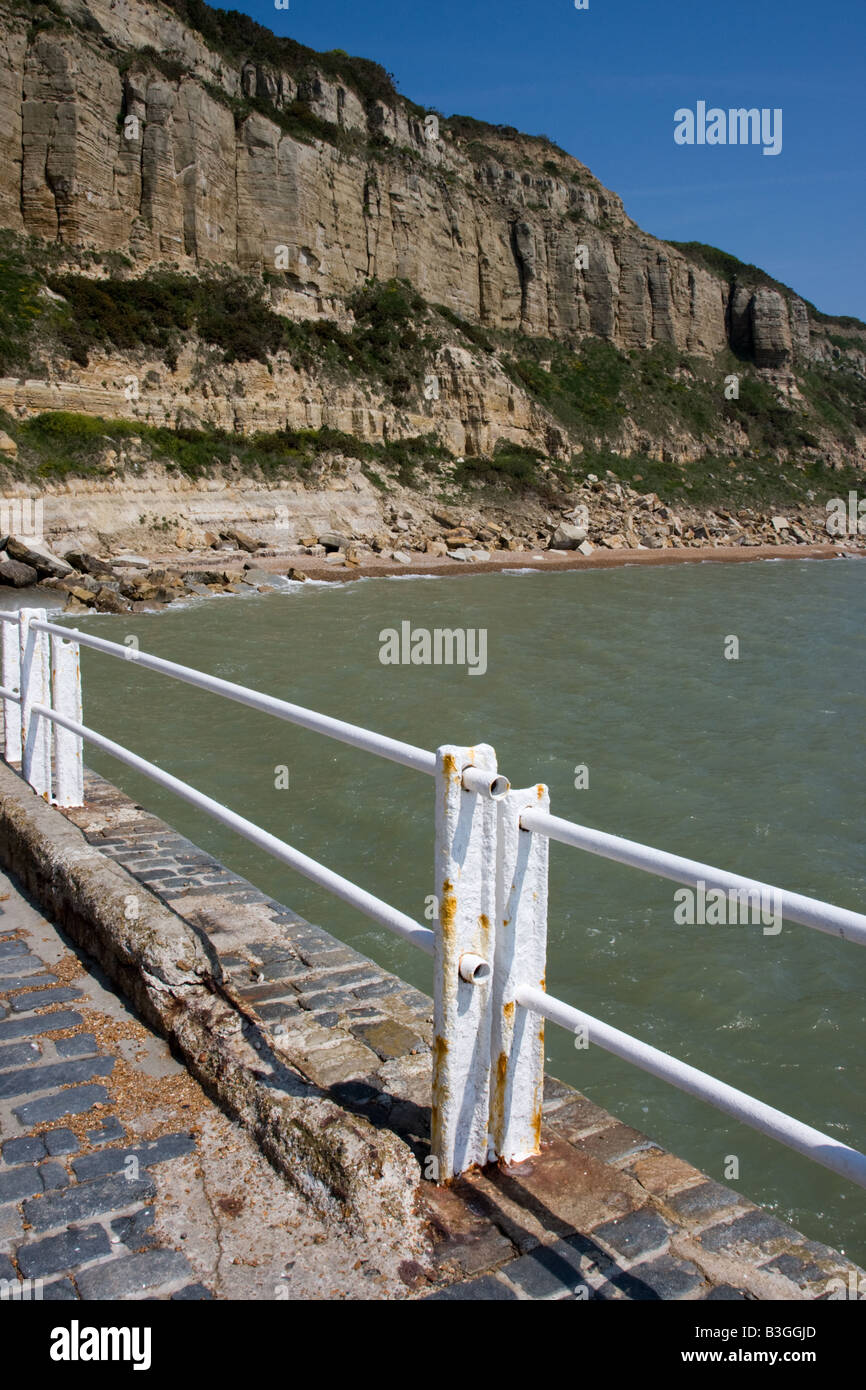 Garde-corps blanc sur le front de mer de Hastings avec les falaises derrière. Banque D'Images