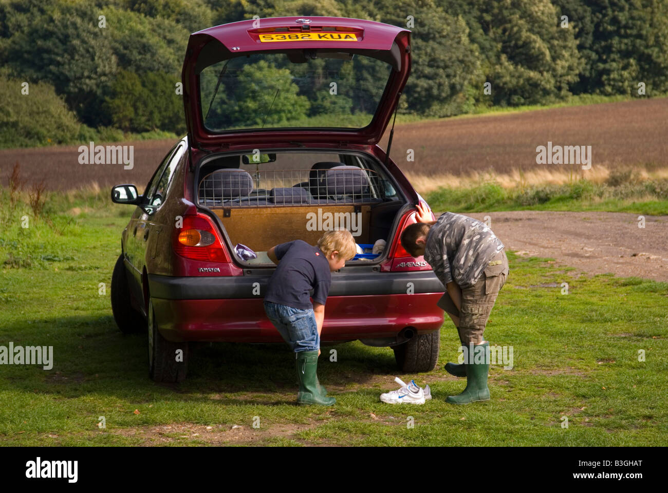 Deux garçons mise sur leurs bottes sur la voiture avant de partir en promenade dans la campagne. Banque D'Images