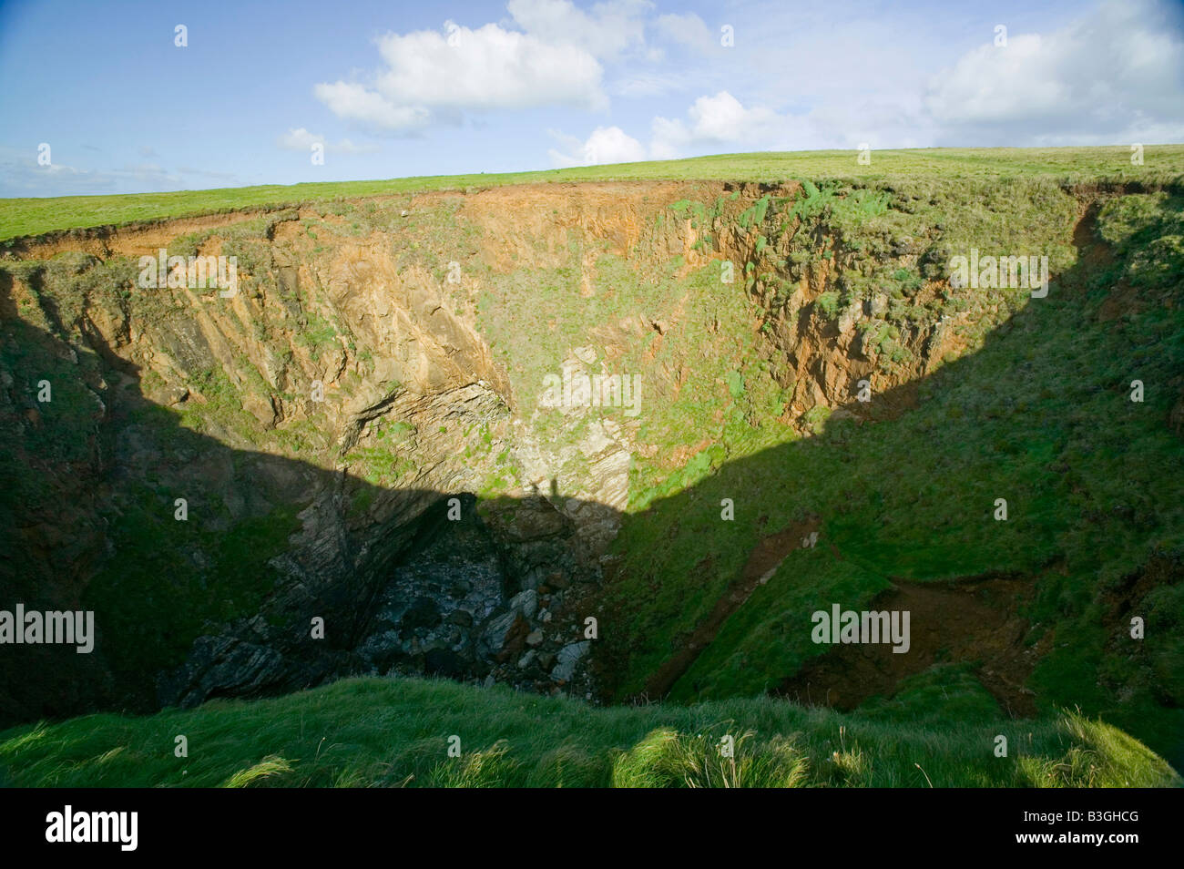 Trou rond à Trevone sur la côte de Cornouailles UK causée par l'effondrement de la toiture d'une grotte marine creusé par l'érosion côtière Banque D'Images