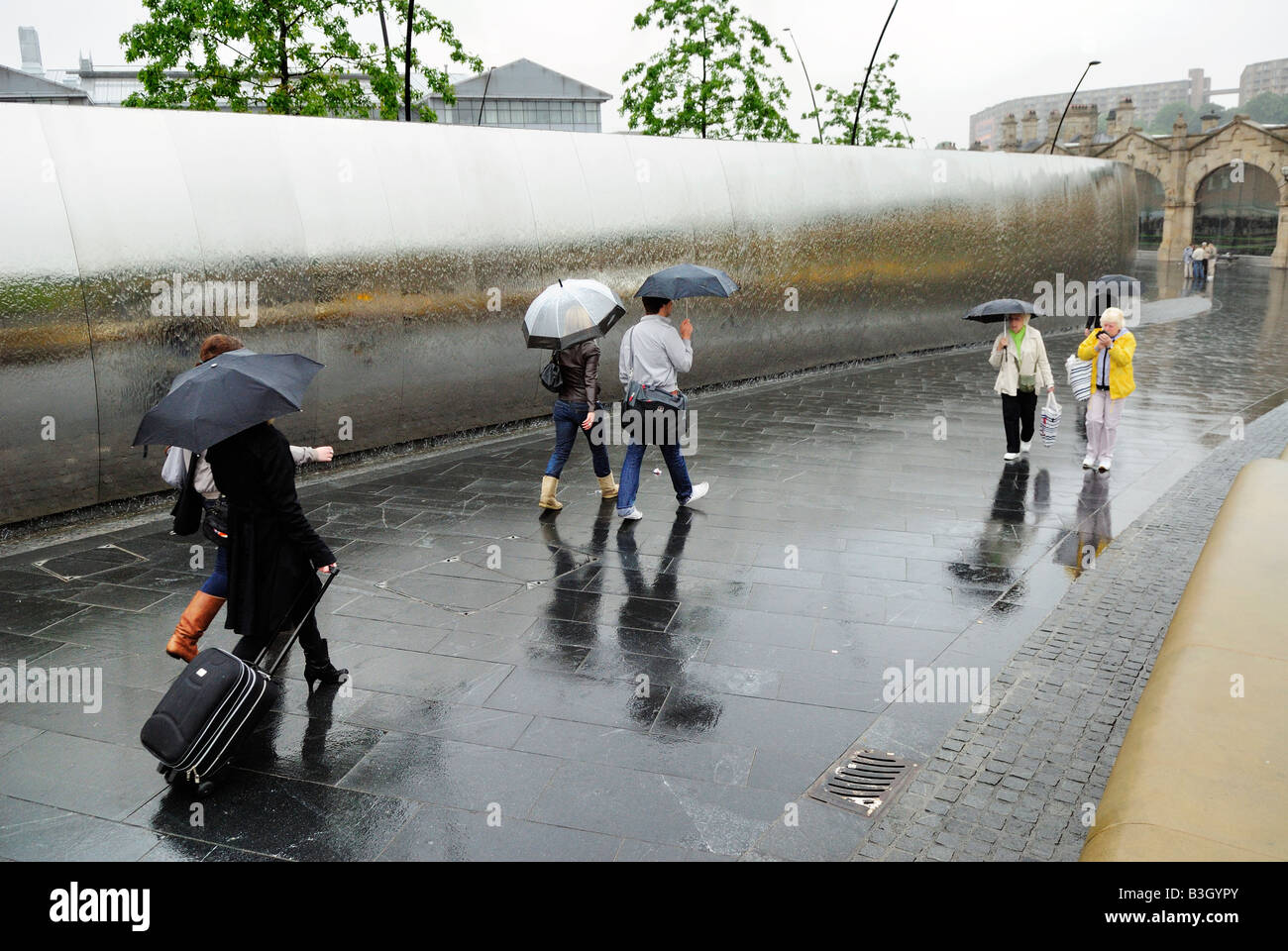 Centre-ville de l'eau à la fine pointe de la sculpture murale et passants avec parasols, Sheffield Banque D'Images