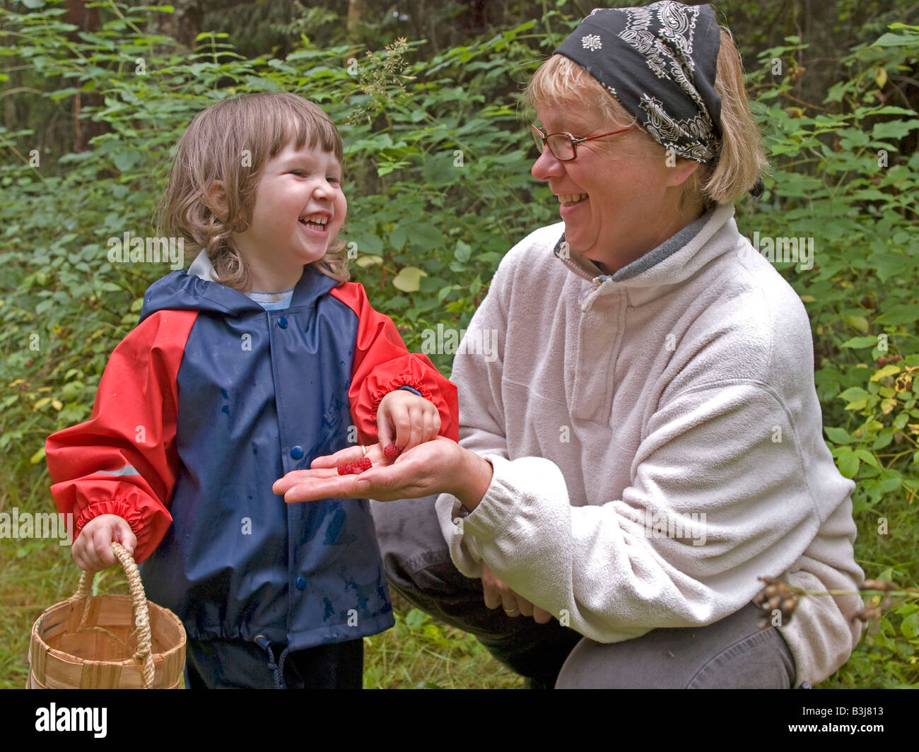 Femme d'âge moyen avec un petit enfant dans l'âge de 3 ans s'amuser par cueillette en forêt les framboises sucrées manger Banque D'Images