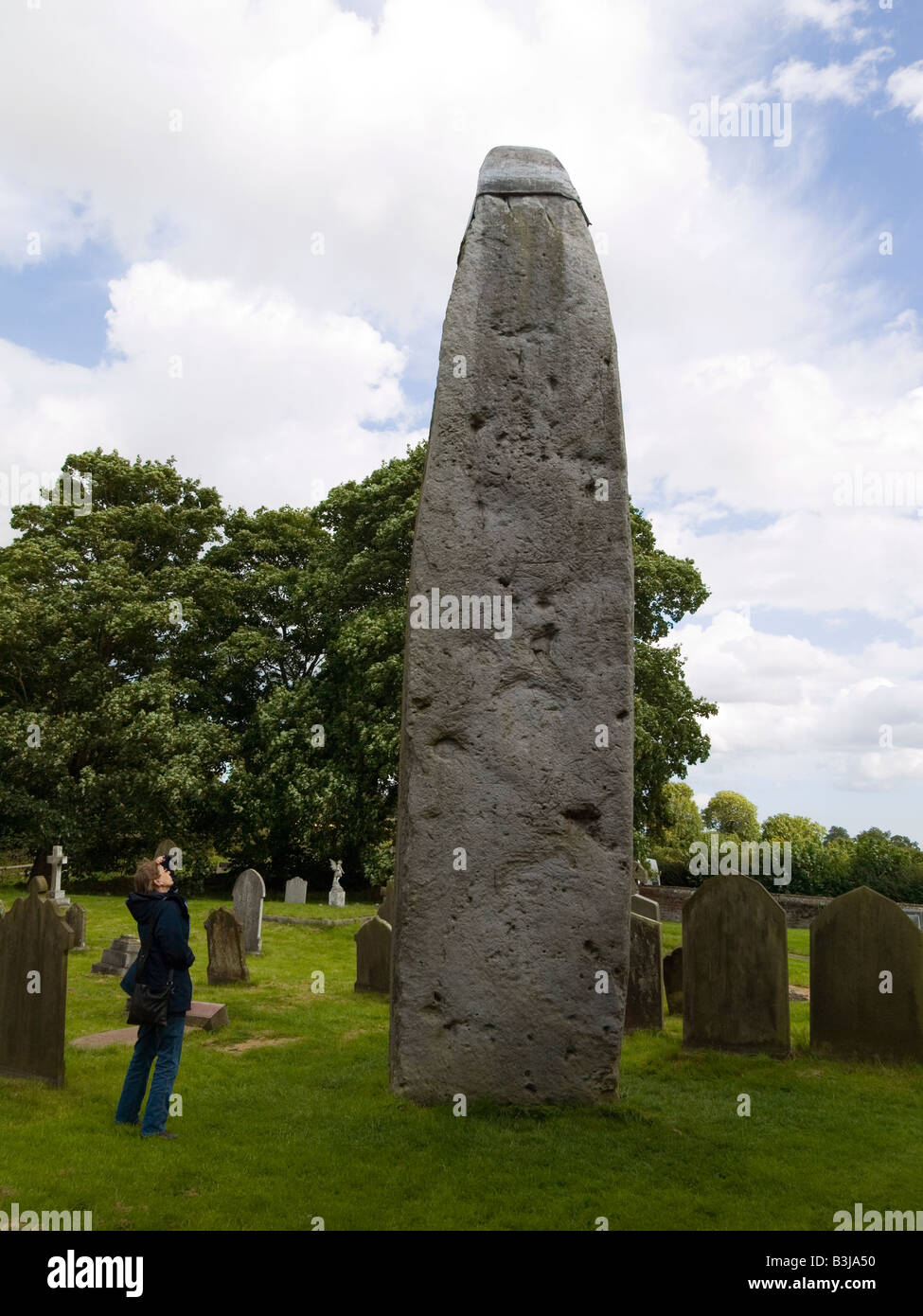 Une femme regarde l'ancien monolithe 76 mètres de haut le plus grand au Royaume-Uni dans le cimetière à Rudston East Yorkshire Banque D'Images