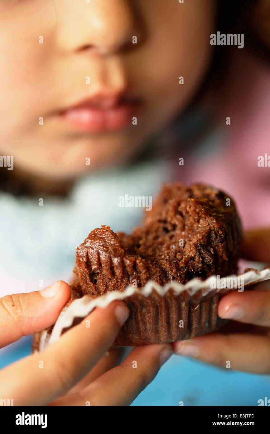 Petite fille de cinq ans mange muffin au chocolat Banque D'Images