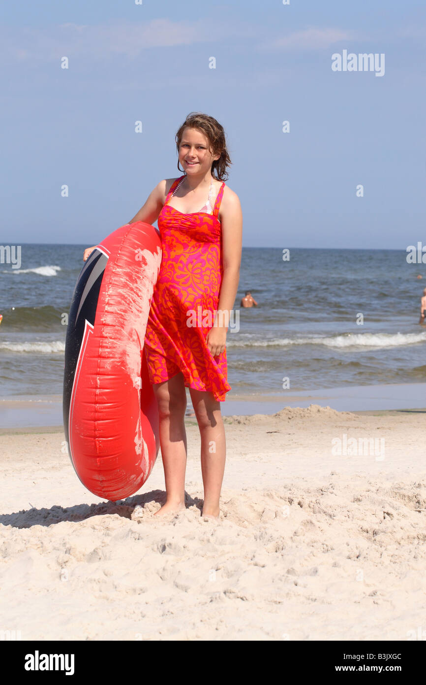 Young woman on beach holiday avec robe rouge et anneau d'air gonflable Banque D'Images