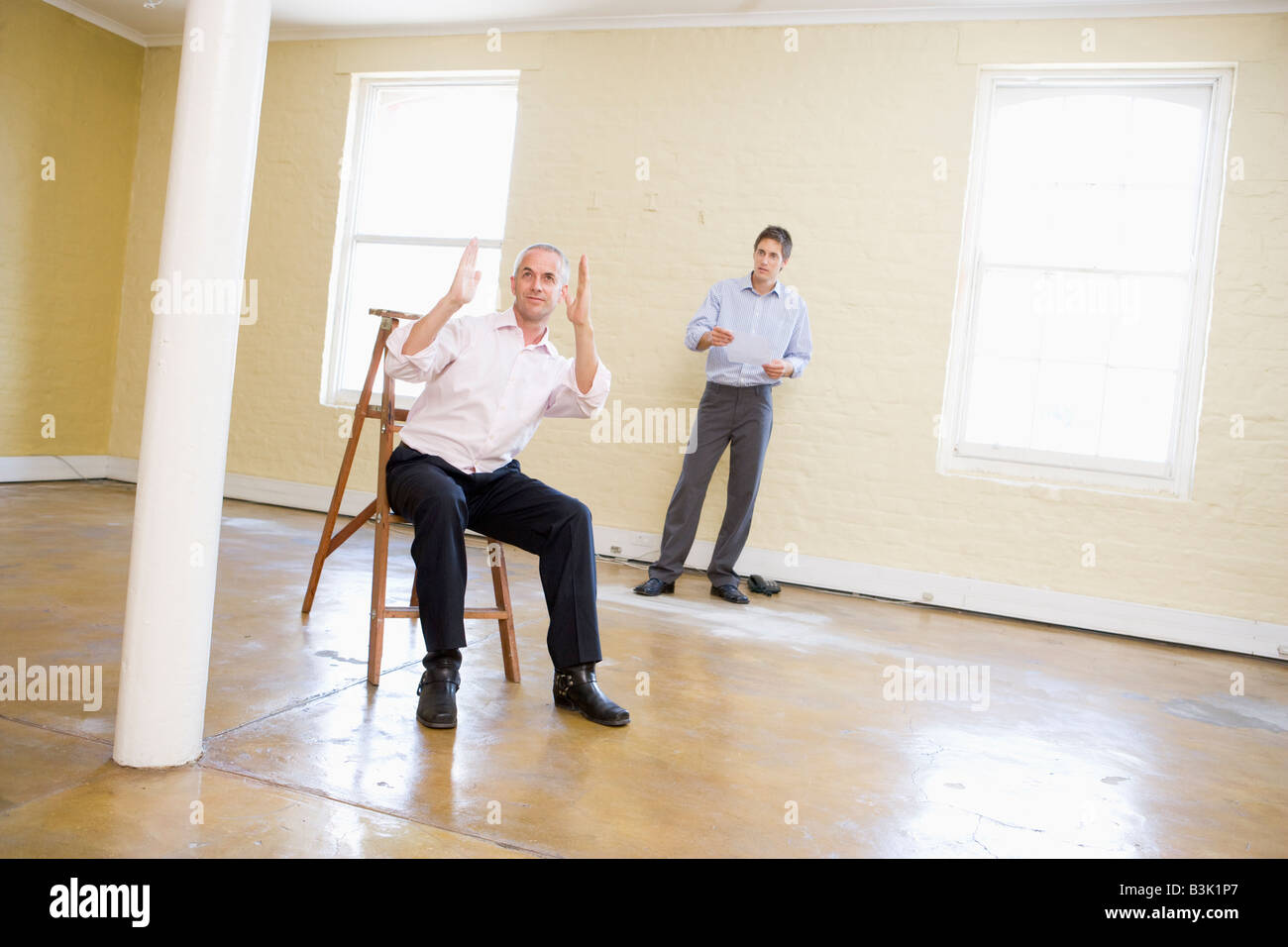 Deux hommes avec échelle dans l'espace vide de faire des plans pour prix Banque D'Images