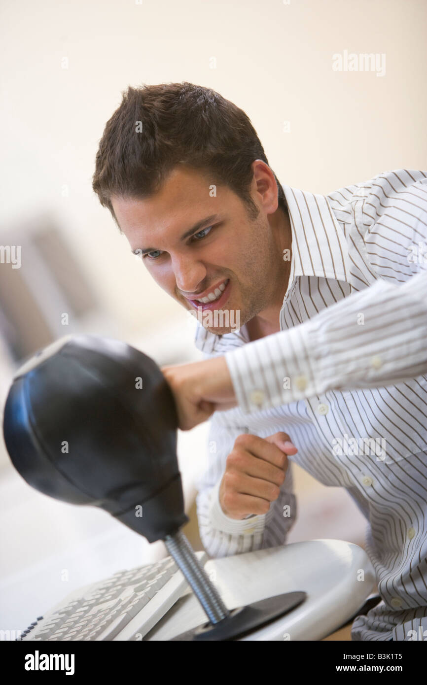 Homme assis dans la salle informatique à l'aide de petits punching bag pour le soulagement du stress Banque D'Images