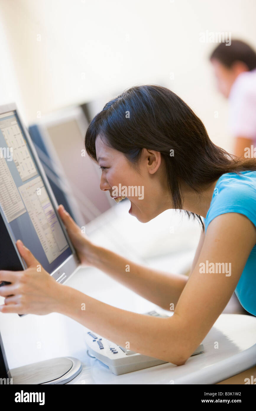Woman in computer room holding monitor and smiling Banque D'Images