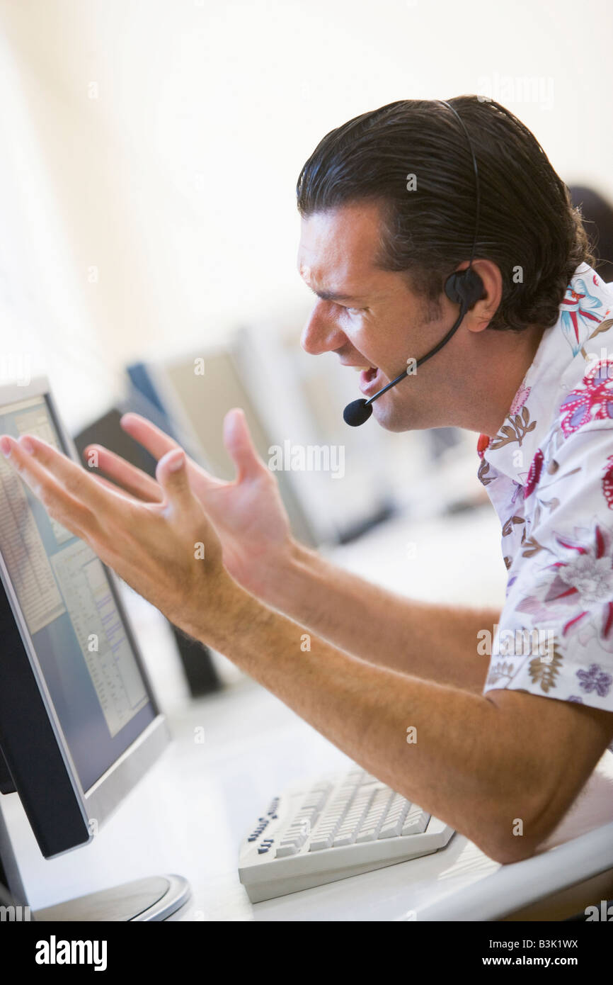 Man in computer room wearing headset à frustré Banque D'Images
