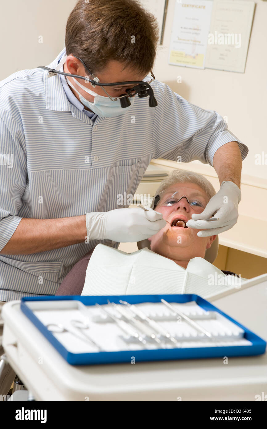 Dentiste dans la salle d'examen avec femme en fauteuil Banque D'Images