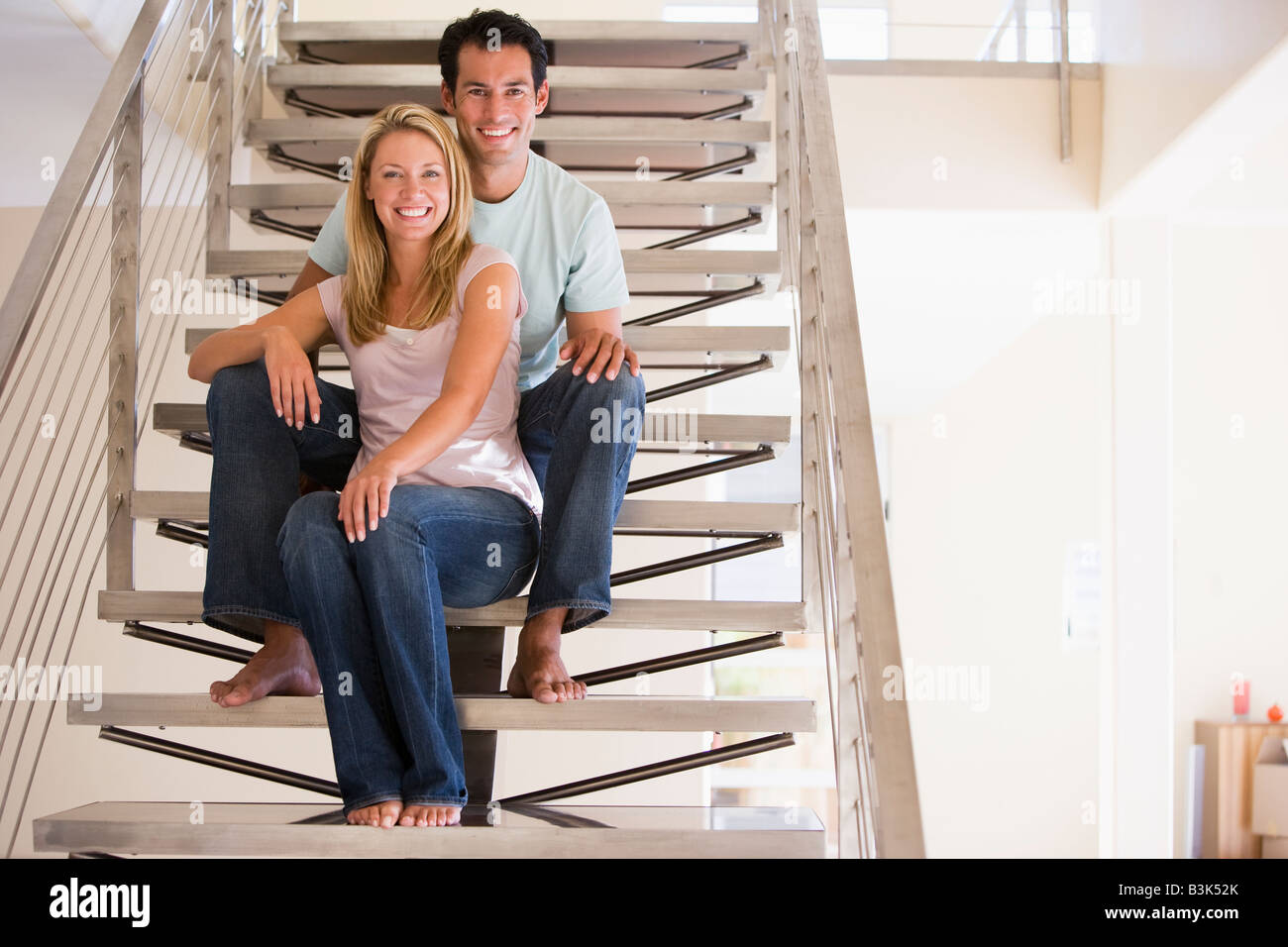 Couple sitting on staircase smiling Banque D'Images