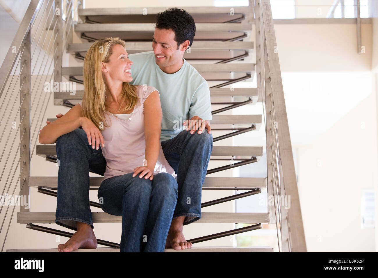 Couple sitting on staircase smiling Banque D'Images