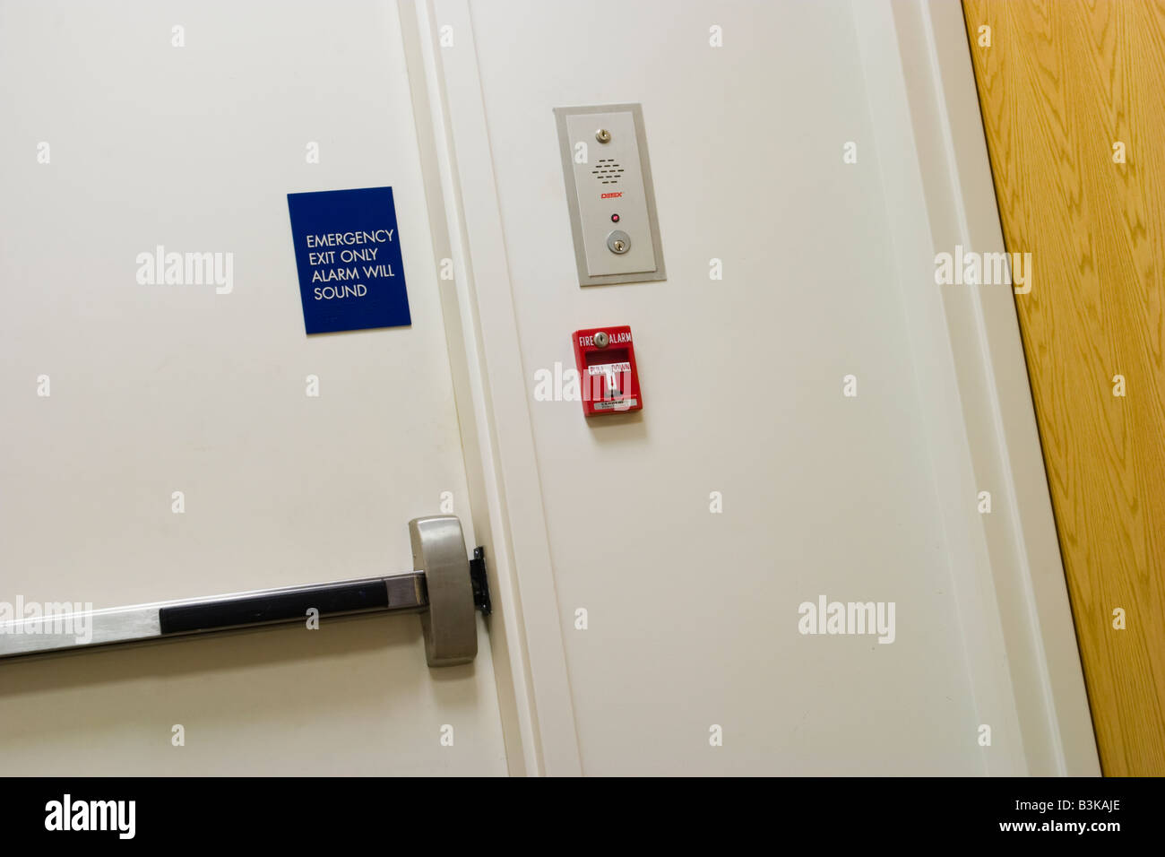 Mur dans un immeuble de bureaux avec un interphone alarme d'incendie et d'un signe indiquant que la porte est une sortie de secours Banque D'Images