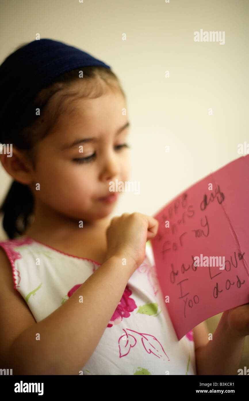 Petite fille de cinq ans est titulaire d'une carte de la fête des pères elle a fait elle-même. 'Happy Father's Day pour mon père J'aime papa yoo'. Banque D'Images