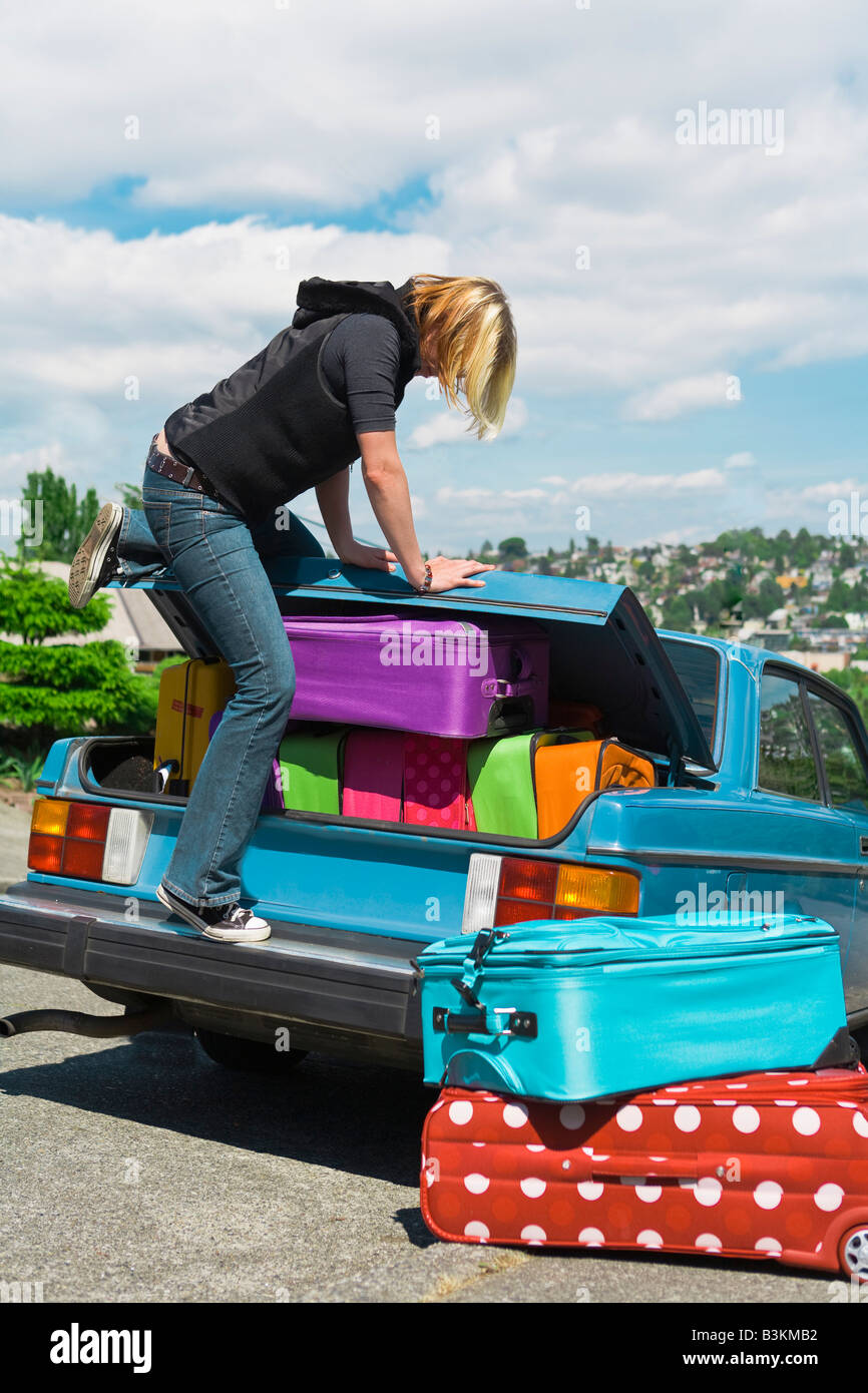 Femme loading coffre de voiture avec des valises Banque D'Images