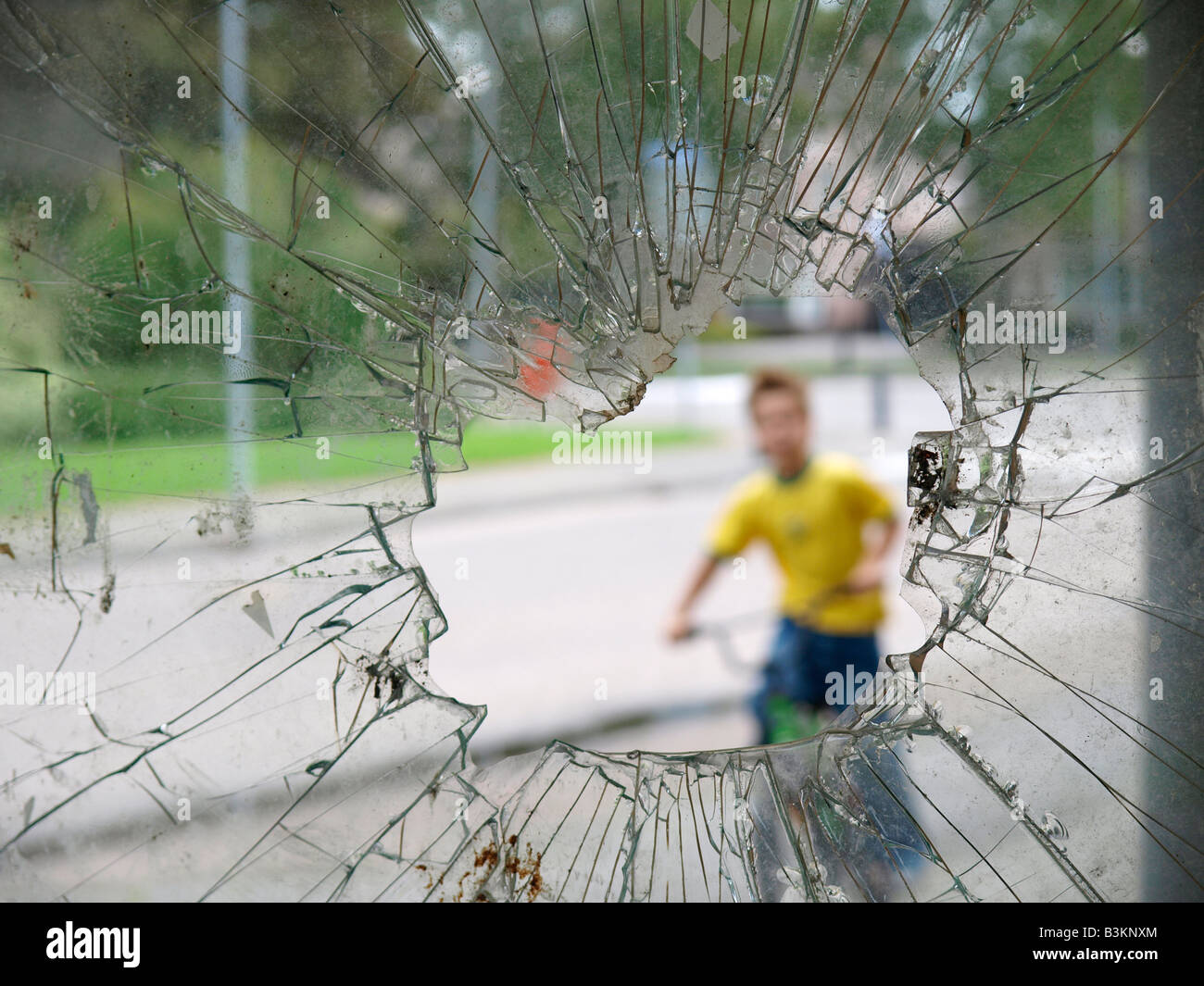 Fenêtre cassée avec garçon floue sur location derrière elle trou le vandalisme Banque D'Images