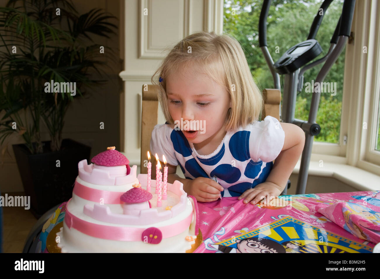 UK 4 year old girl blowing out candles on cake Banque D'Images