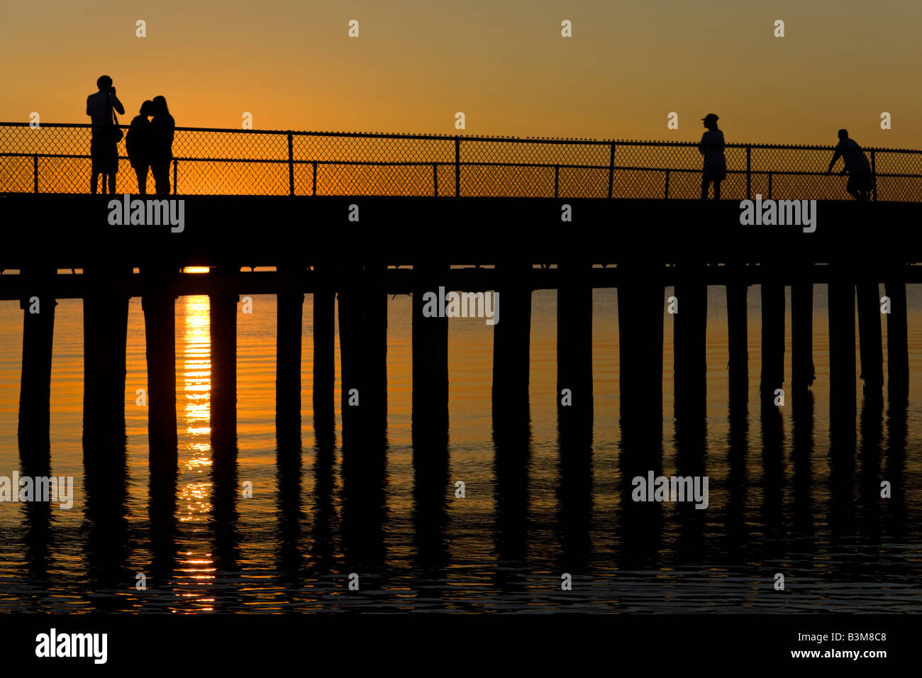 Sunset Silhouette de touristes sur la jetée de pêche avec des paillettes chemin de soleil réfléchi sur la baie du Delaware. Banque D'Images