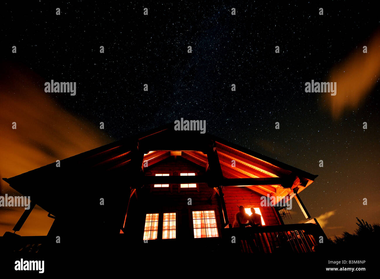 La Voie lactée s'étend au-dessus d'une cabane en bois comme deux résidents admirer l'impressionnant ciel nocturne au-dessus de Inverness, Écosse Banque D'Images